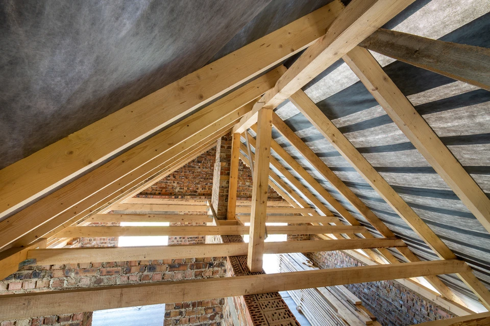 Chantier de construction résidentielle montrant la charpente en bois d'une toiture en cours d'assemblage