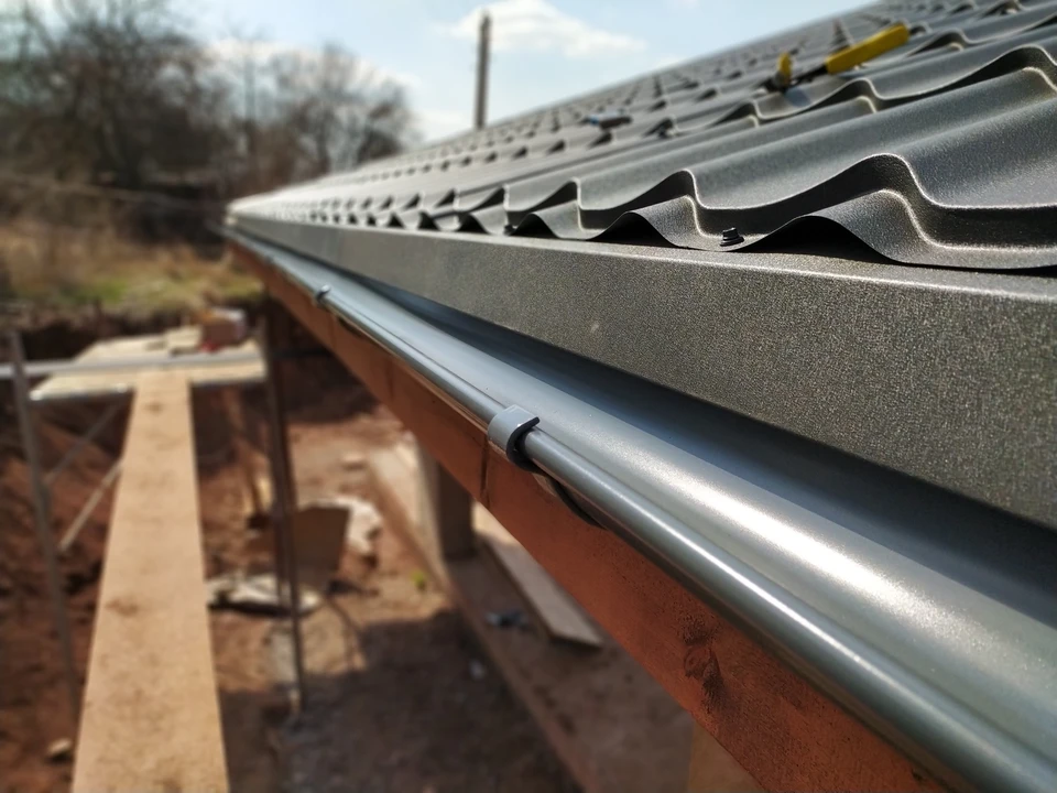 Extérieur d'une habitation avec toiture en cours de rénovation, échelle en bois positionnée contre la façade