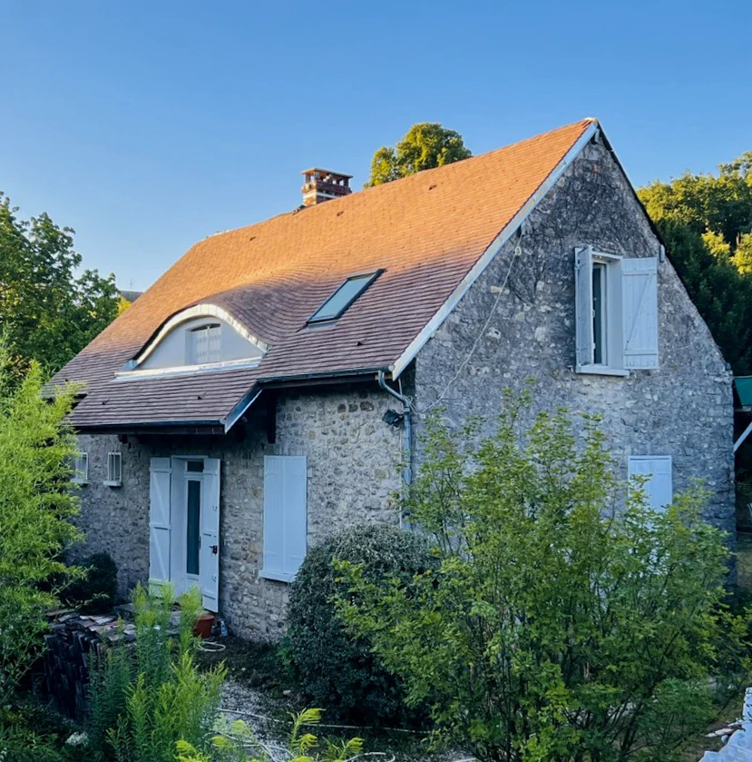 Chantier de rénovation de toiture en extérieur avec ouvrier travaillant sur structure en cours de réfection