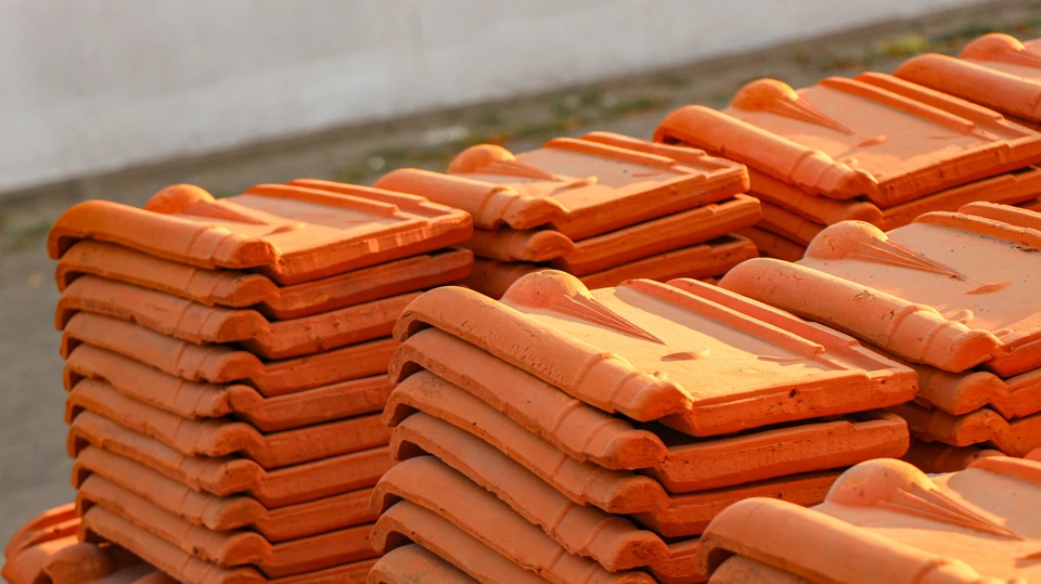 Ouvrier couvreur en silhouette travaillant sur une toiture inclinée contre un ciel bleu nuageux avec lune visible