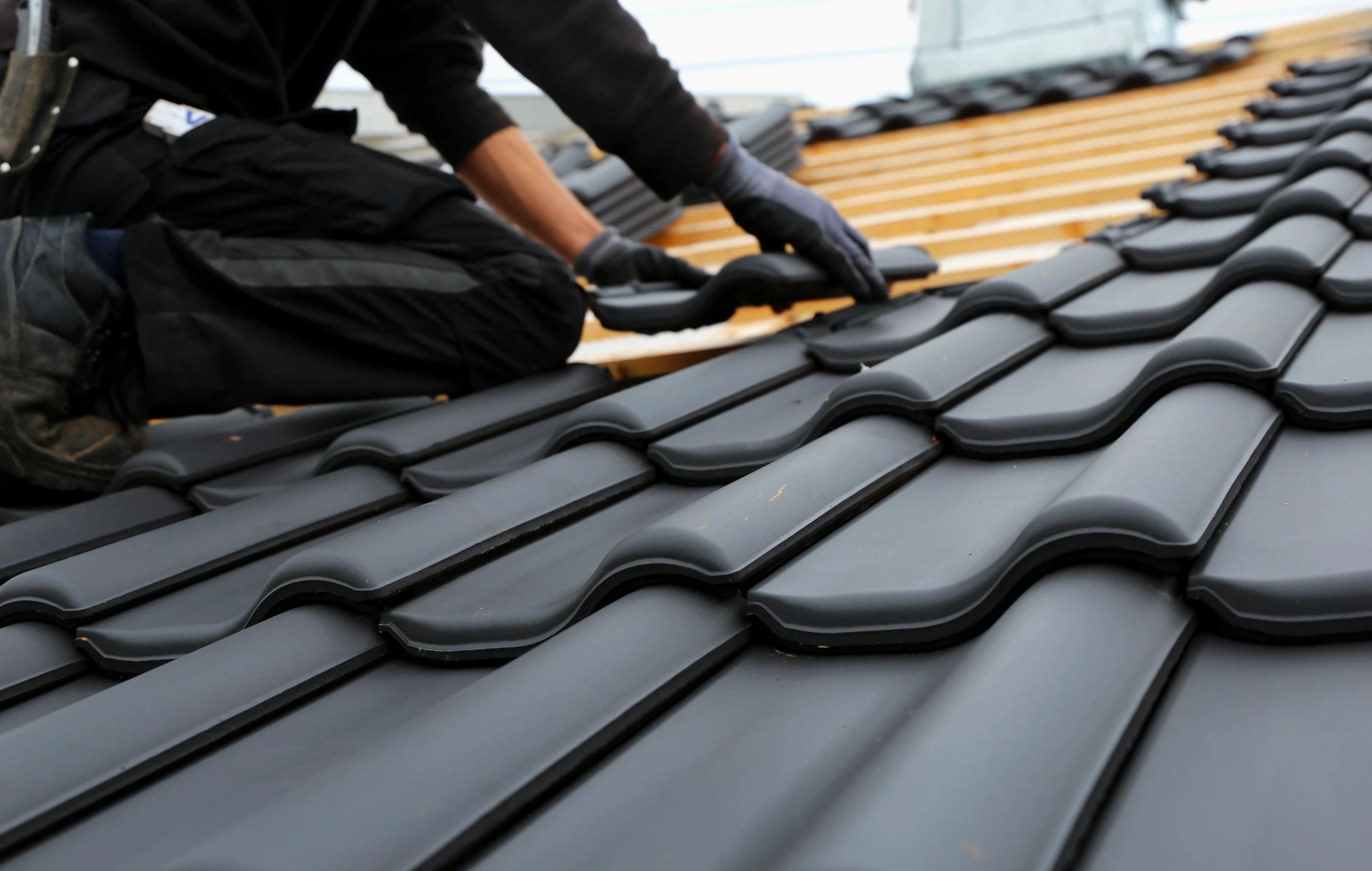 Couvreur professionnel installant des tuiles m&eacute;talliques sur une toiture r&eacute;sidentielle
