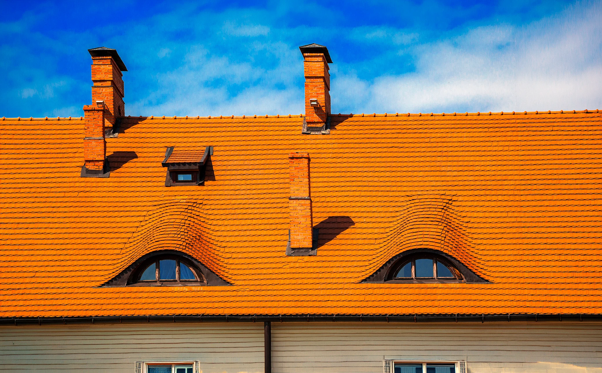 Couvreur professionnel installant des tuiles terre cuite sur toiture en pente