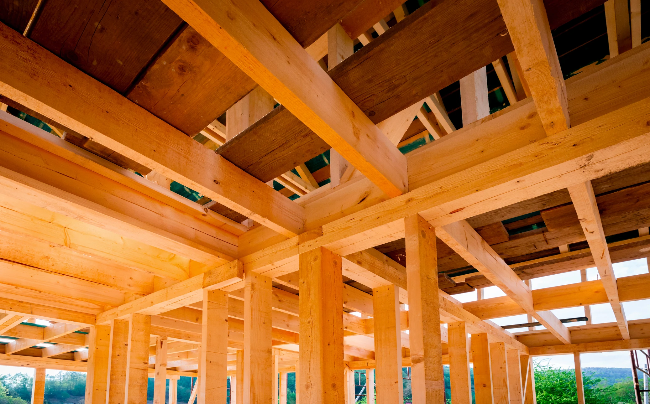 Maison contemporaine en forêt illuminée au crépuscule, architecture moderne avec façade vitrée triangulaire et structure bois